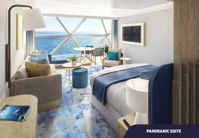 Foto da cabine Panoramic Suite com cama, sofá, escrivaninha e janela com vista para o mar